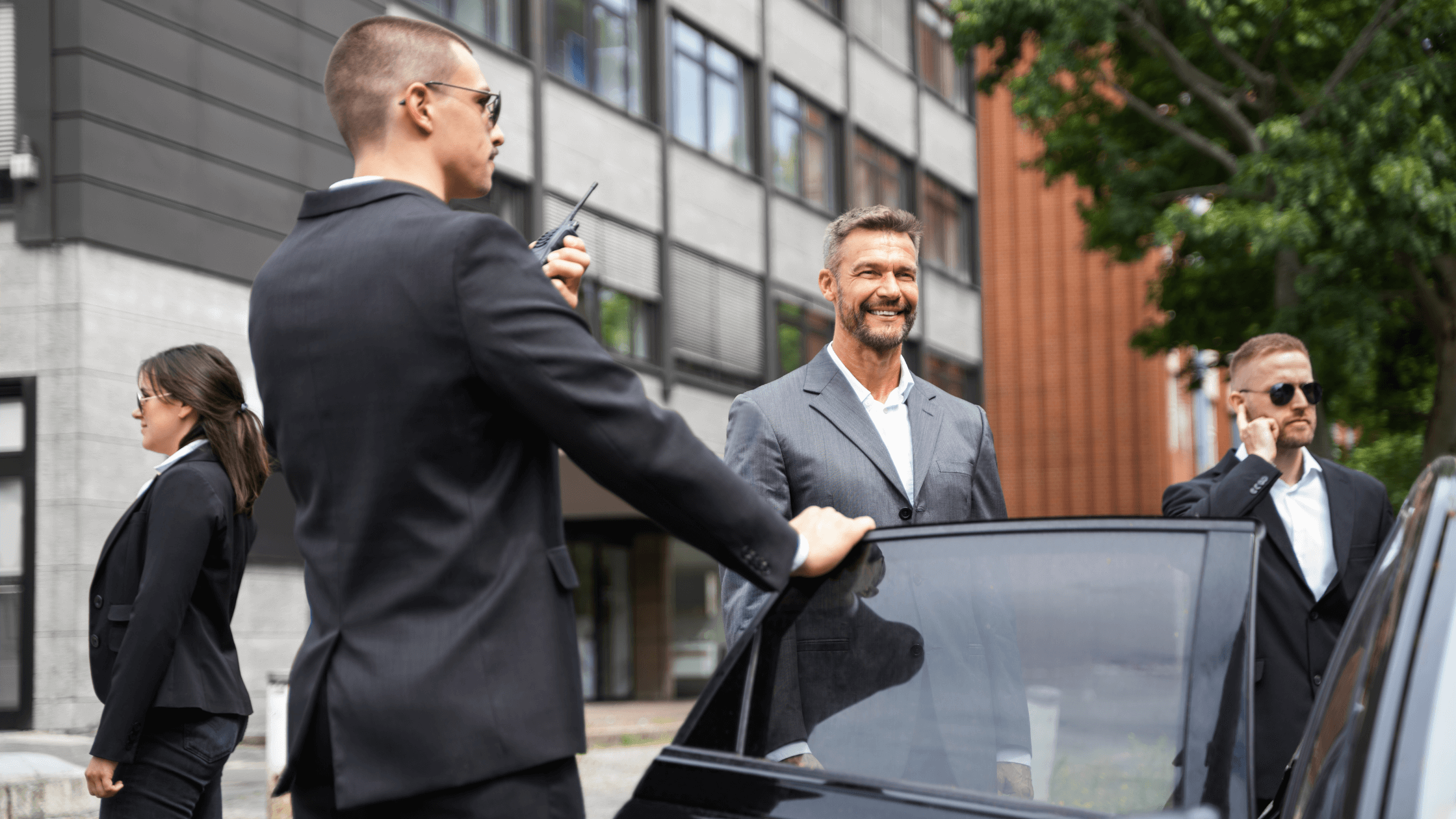 Steve, a security professional, holding a radio while protecting a client getting into a car, symbolizing a successful career transition from service to the in-demand security field.