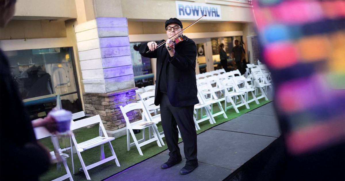 Nico playing the violin at an outdoor event, representing a successful and fulfilling creative service trade career in music performance.