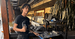 Niko giving a thumbs-up while standing next to an audio mixing board, symbolizing a successful and rewarding creative trade career in music technology.