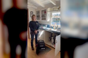 Plumbing career inspiration — Christina, a plumbing technician wearing her tool belt at a residential kitchen job, four years into a trade she started through paid on the job training