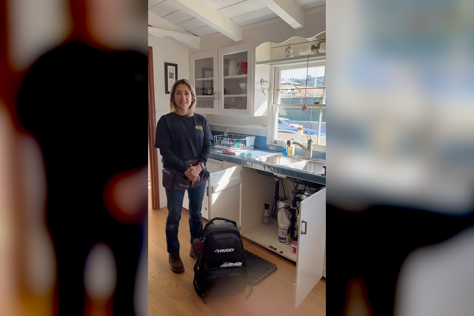 Plumbing career inspiration — Christina, a plumbing technician wearing her tool belt at a residential kitchen job, four years into a trade she started through paid on the job training
