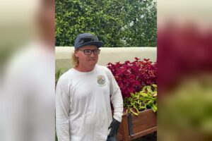 Chris, a pest control operator and business owner, standing in a garden in his company shirt