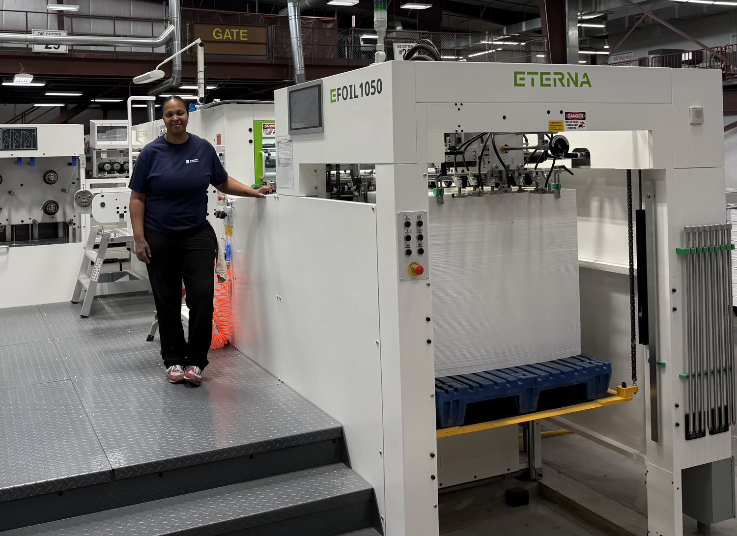 Techelle standing beside the multimillion-dollar ETERNA foil stamping machine she operates